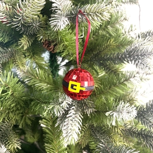 Sparkly red Santa suit disco ball ornament with belt hanging on frosted Christmas tree