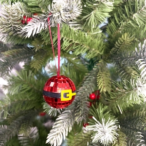 Close-up of red mirror disco ball Christmas ornament with Santa belt hanging on a tree