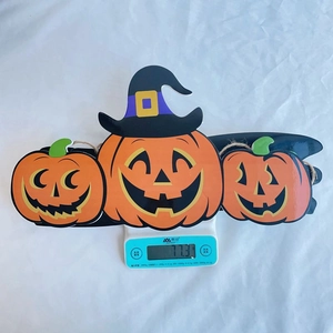 Detailed view of lightweight Halloween pumpkin door hanger weighing 77.3g on scale