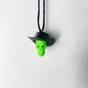 Detail of neon green skull pendant with black cowboy hat and woven lanyard cord
