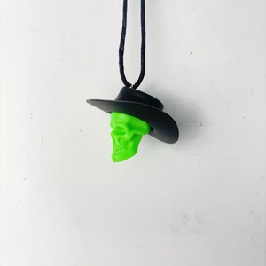 Detail view of a bright green skull pendant with black cowboy hat and hanging cord