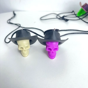 Detail of ivory and purple skeleton charms wearing cowboy hats with black hanging ropes