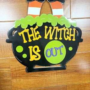 Detail of Halloween witch cauldron sign with striped legs on a wooden background