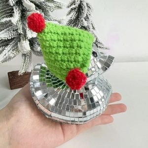 Close-up of disco ball duck ornament with green knitted hat in a snowy Christmas scene