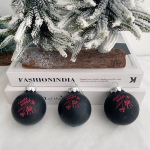 Close-up of matte black Halloween ornaments featuring a bloody handprint and Wanna Play text