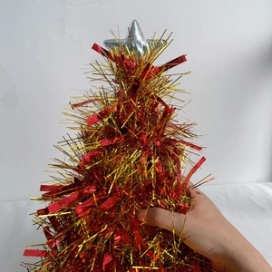 Close-up of a mini Christmas tree ornament with red and yellow tinsel and silver star