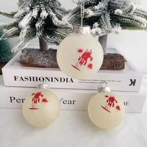 Detail of three cream Halloween balls with red blood handprints on mini snowy pine trees