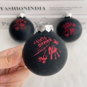 Detail of a matte black Halloween ornament with a red bloody handprint and text