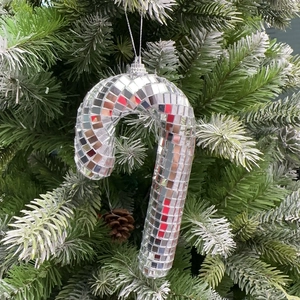 Close-up of a silver mirror disco ball candy cane ornament on a green Christmas tree