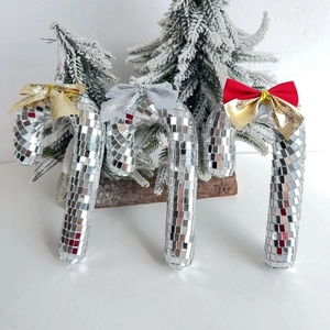Disco mirror ball candy cane Christmas ornaments with glitter bows on snowy background