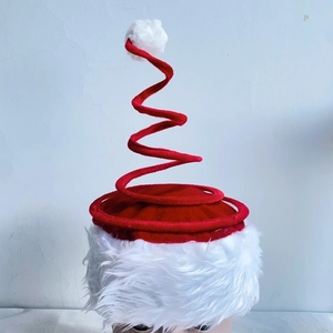 Close-up of a festive Christmas spiral spring hat with red velvet and plush white trim