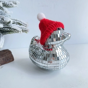Close-up of disco ball glass duck with red Christmas hat and festive pine branches decor