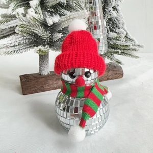 Close-up of a snowman disco ball with a red knit hat and scarf on a wooden base