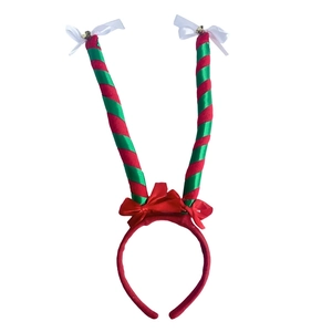 Detail of red and green striped elf legs headband with festive bows and golden bells