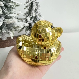 Close-up of golden disco mirror duck figurine held in hand for decorative scale display
