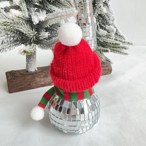 Detail of disco ball snowman with red knit hat and scarf in a festive winter scene