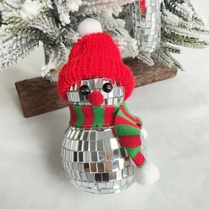 Close-up of Disco ball snowman ornament with red knitted hat and striped scarf