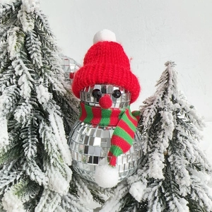 Christmas snowman disco ball ornament with red hat and striped scarf on pine branch