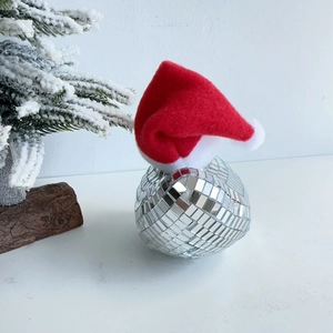 Close-up of disco ball glass bird ornament with red Christmas hat and silver mirror scales