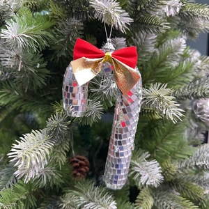 Disco mirror ball candy cane Christmas ornament with red gold bow on a snowy tree