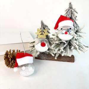 Detail of transparent Christmas baubles with reindeer antlers and red Santa hats with snow