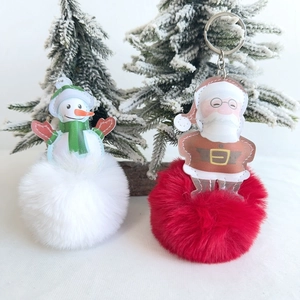 Detail of plush Christmas keychains with Santa and snowman charms on fluffy fur balls