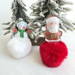 Detailed view of plush Santa and Snowman keychains with soft faux fur pom-poms