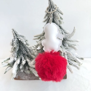 Detail of Christmas Santa plush ball keychain hanging on a snowy tree branch