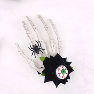 Détail de la pince main squelette avec rose noire, araignée et œil ensanglanté