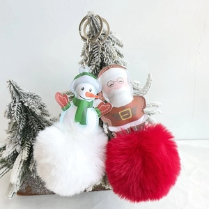 Close-up of fluffy faux fur Santa and Snowman pompom keychains for Christmas decor