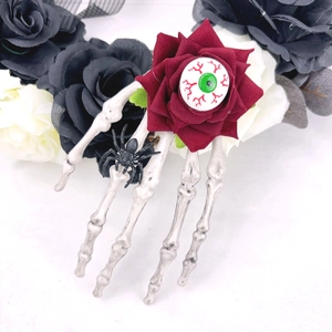 Détail d'une pince à cheveux main de squelette avec rose rouge et œil sanglant