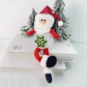 Detail of Santa Claus LED plush ornament with glowing snowflake belly sitting on books