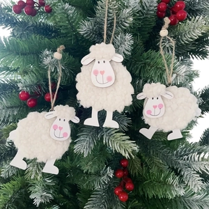 Detailed close-up of three wool felt sheep ornaments hanging on a green Christmas tree branch