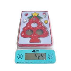 Miniature wooden Christmas tree ornament weighing 42.9 grams on a precise digital scale