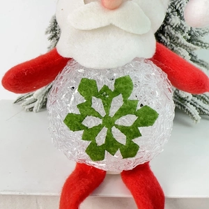 Close-up of Santa Claus LED ornament with red felt hat and glowing acrylic snowflake belly