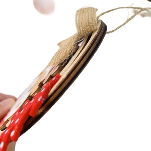 Detail view of layered wooden Christmas ornament with laser-cut edges and red polka dot fabric
