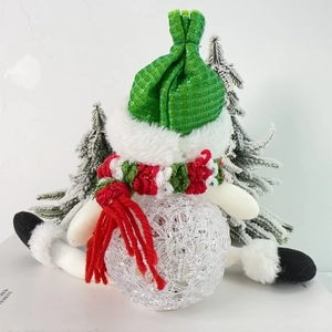 Close-up of a Christmas snowman LED light with a red and green knit hat and striped scarf