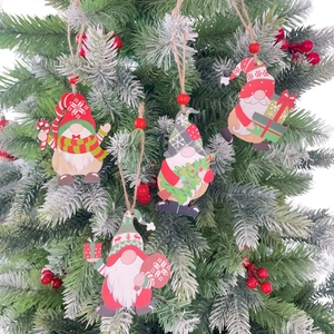 Close-up of four wooden Christmas gnome ornaments hanging on a snowy tree branch
