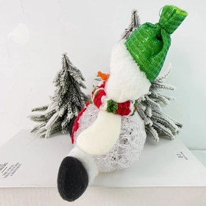 Detailed view of plush Christmas snowman ornament with green knit hat and striped scarf