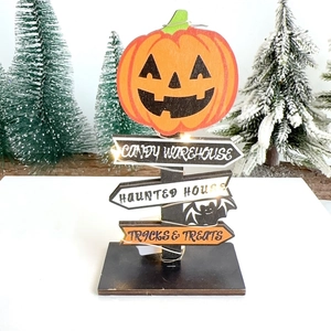 Detail of wooden Halloween sign with LED lights, pumpkin top and festive text on base