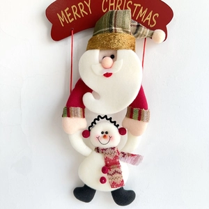 Detail von Weihnachtsmann und Schneemann Hängedeko mit Merry Christmas Schild auf weißer Wand