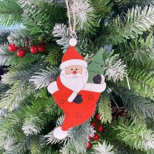 Hanging wooden Santa Claus ornament in a red boot on a decorated Christmas tree branch