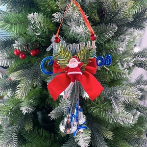 Detail of Christmas ornament with Santa doll, red bow, and silver bells on a tree