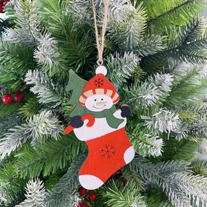 Detail of wooden snowman in red Christmas stocking ornament hanging on a pine tree branch