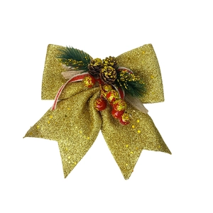 Detail of gold glitter Christmas bow with pine cones and berries on white background
