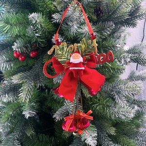 Close-up of a Merry Christmas ornament with Santa, a bow, and three pink bells on a tree