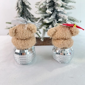 Close-up of brown plush bears with mirror disco balls and colorful silk bows