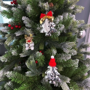 Detail of silver sequined Christmas tree ornaments with red bows and festive hats