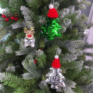 Close-up of glittery Christmas tree and disco ball reindeer ornaments on a snowy tree