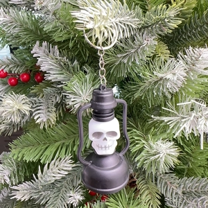 Detail of vintage skull lantern keychain hanging on festive pine branch background